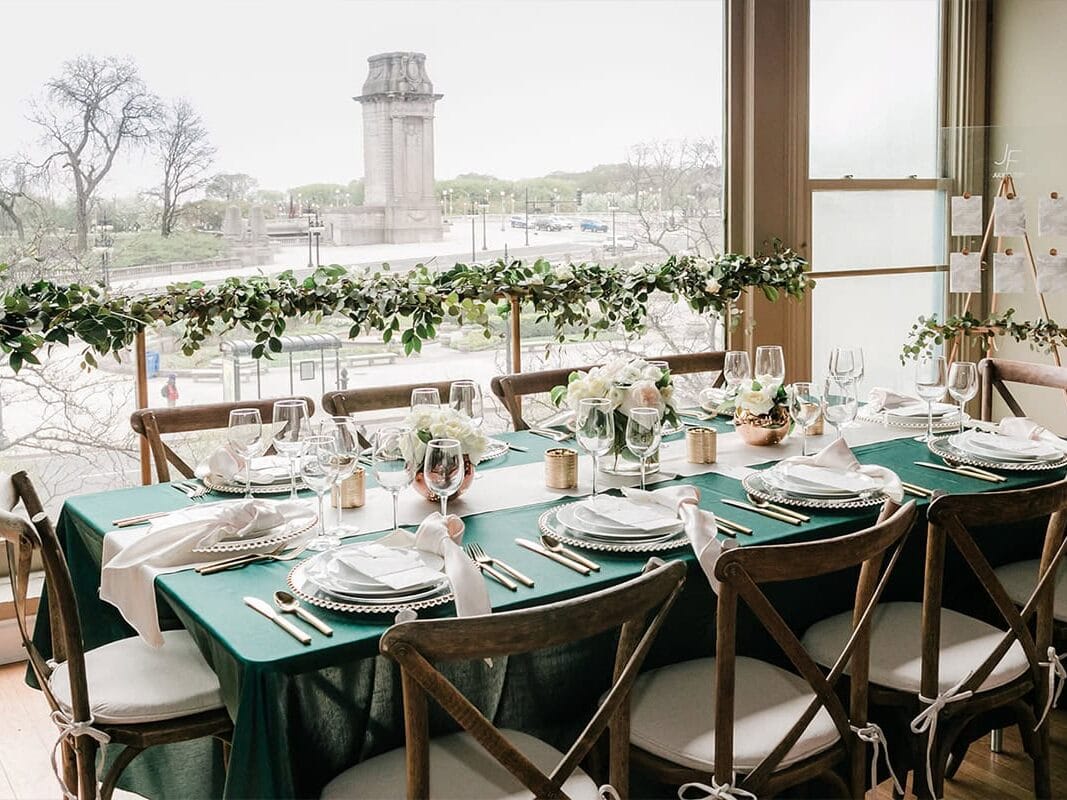Table with green tablecloth, wooden chairs, and garland with city view at Austin TX wedding 