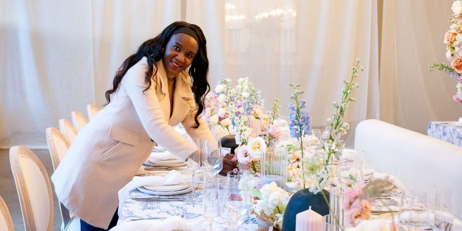 QC Event School graduate and certified luxury destination wedding planner Grace Johnstone setting a floral reception table, showcasing expertise in how to plan a destination wedding.