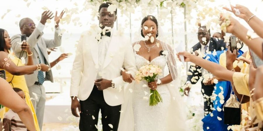 Couple celebrating their ceremony with flower petals at a tropical venue, showing how to plan a destination wedding in Mexico with guests.