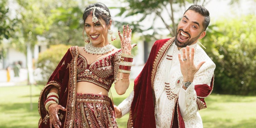 Smiling couple in traditional attire celebrating their big day outdoors, showcasing how to plan a destination wedding with cultural traditions.
