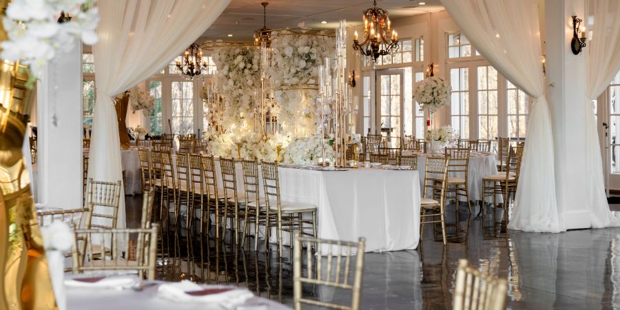 Elegant wedding reception setup with gold chairs, chandeliers, and white floral décor, showcasing how to start an event planning business with luxury design ideas. Planned by Tyler Reid of Eminent Events. Photography by A Love Experience.