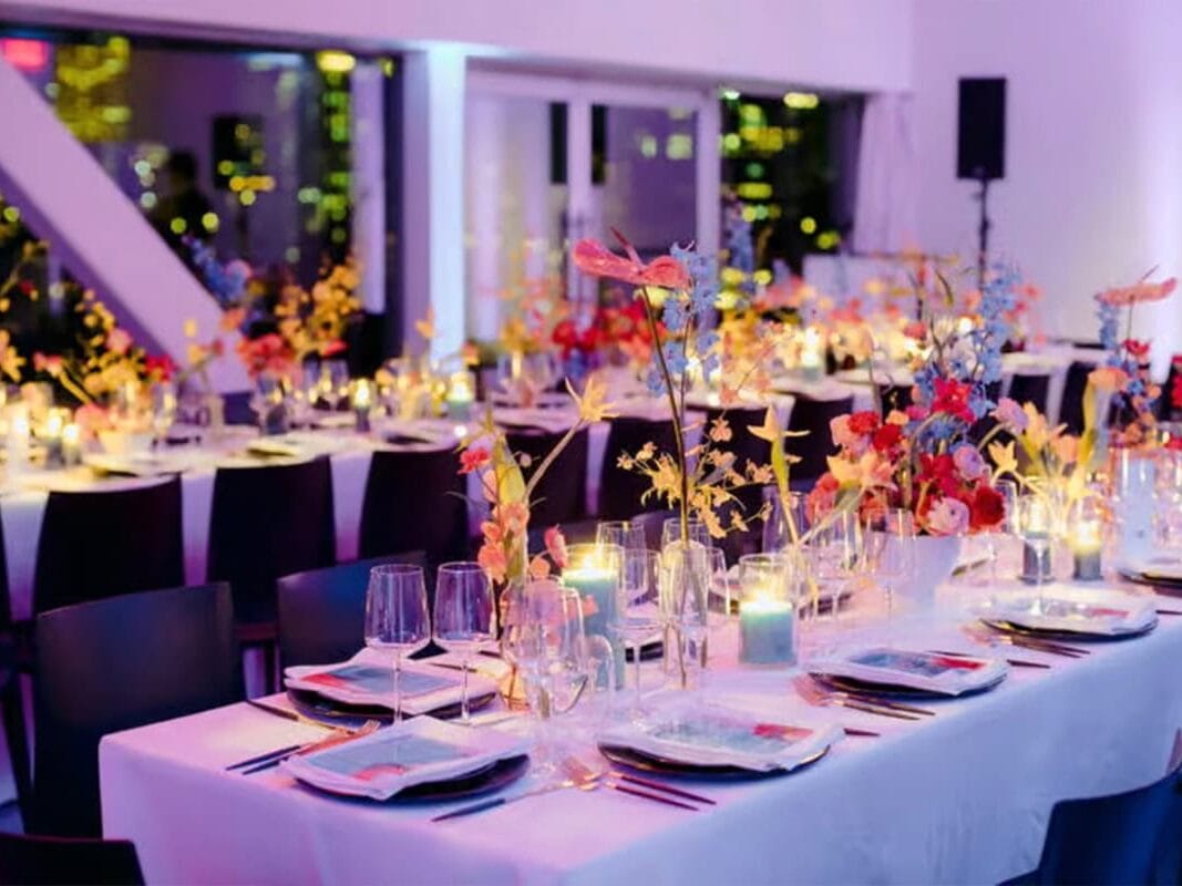 Indoor Houston wedding venue with purple hued light, colorful florals, and tables