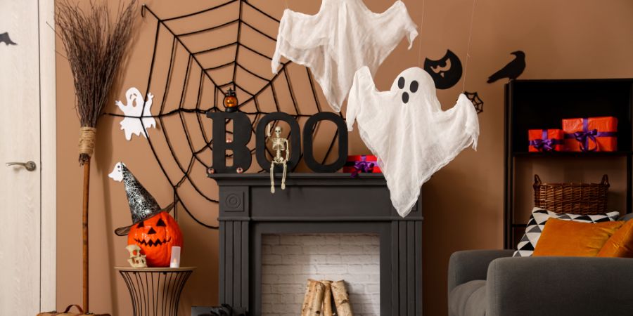 Halloween party ideas with ghost decorations, spiderweb wall, pumpkin with witch hat, and spooky mantel setup for festive home decor.