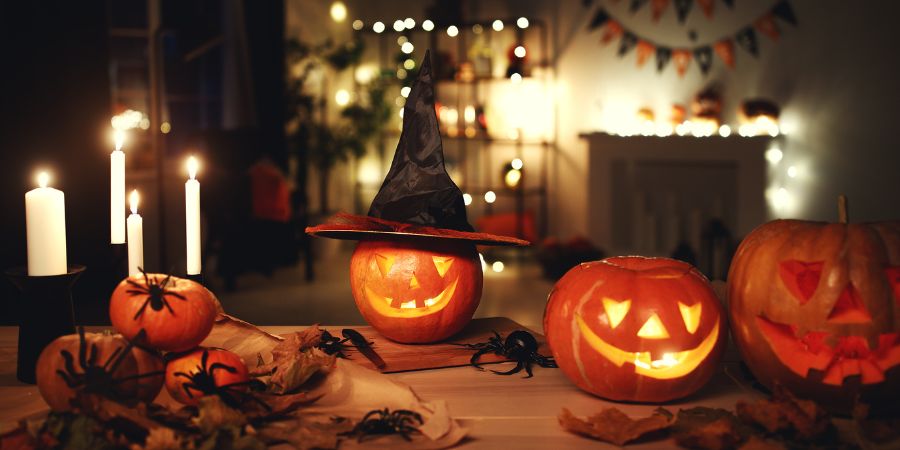 Halloween party ideas with glowing jack-o’-lanterns, candles, and festive decorations creating a cozy spooky atmosphere indoors.