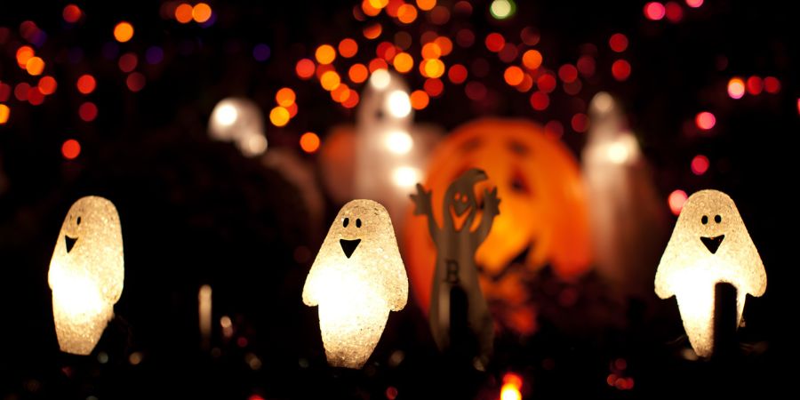 Halloween party ideas with glowing ghost lights, festive pumpkins, and colorful string lights creating a spooky outdoor atmosphere.
