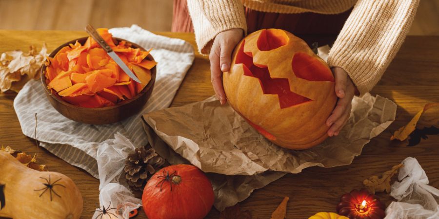 Halloween party games activity with a child carving a jack-o’-lantern pumpkin as part of festive DIY fun.
