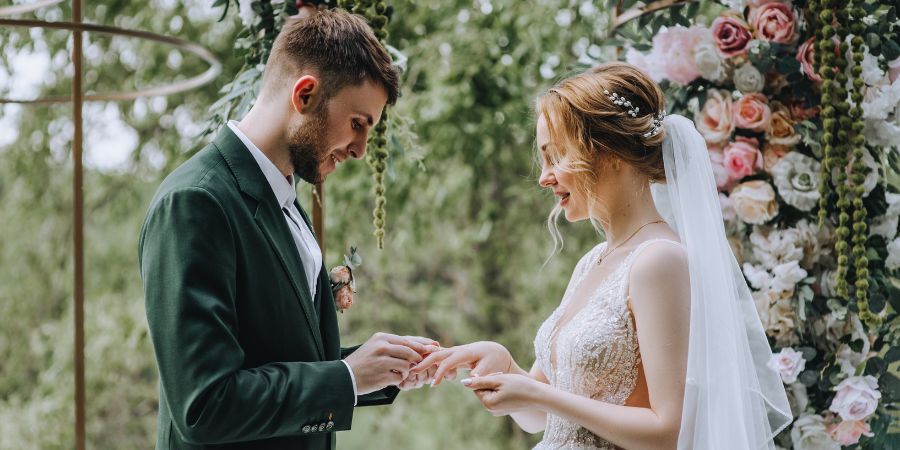 Bride and groom exchanging rings during a wedding ceremony, an example of what planners organize when learning how to become a wedding planner.