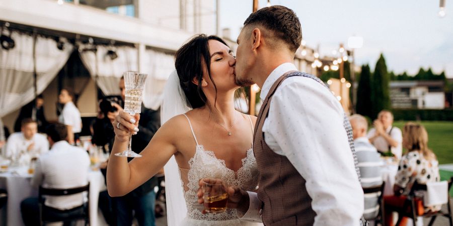 Bride and groom kissing during their wedding reception, a moment organized by professionals for those learning how to become a wedding planner.