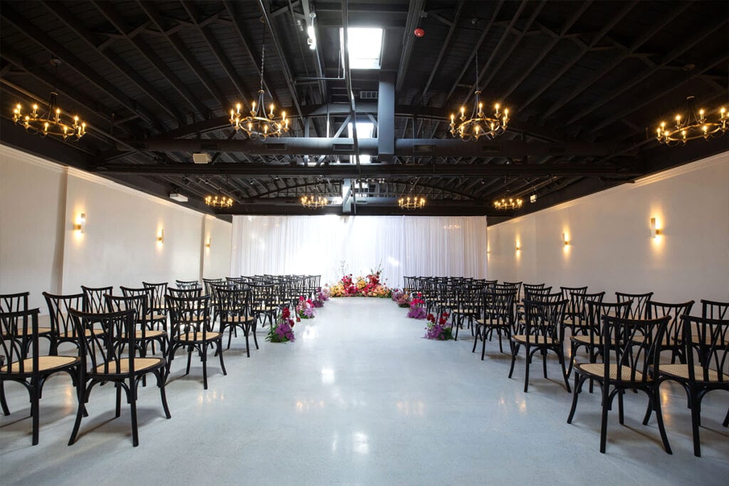 Large indoor Dallas wedding planned with black chairs, white drapery, chandeliers