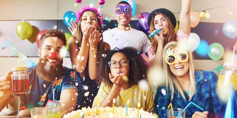 Group of friends celebrating with balloons, confetti, and drinks, showing how to plan a birthday party that feels fun and memorable.