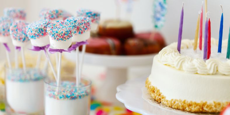 Birthday cake with colorful candles and sweet treats on display, inspiring creative birthday party ideas for desserts and decorations.