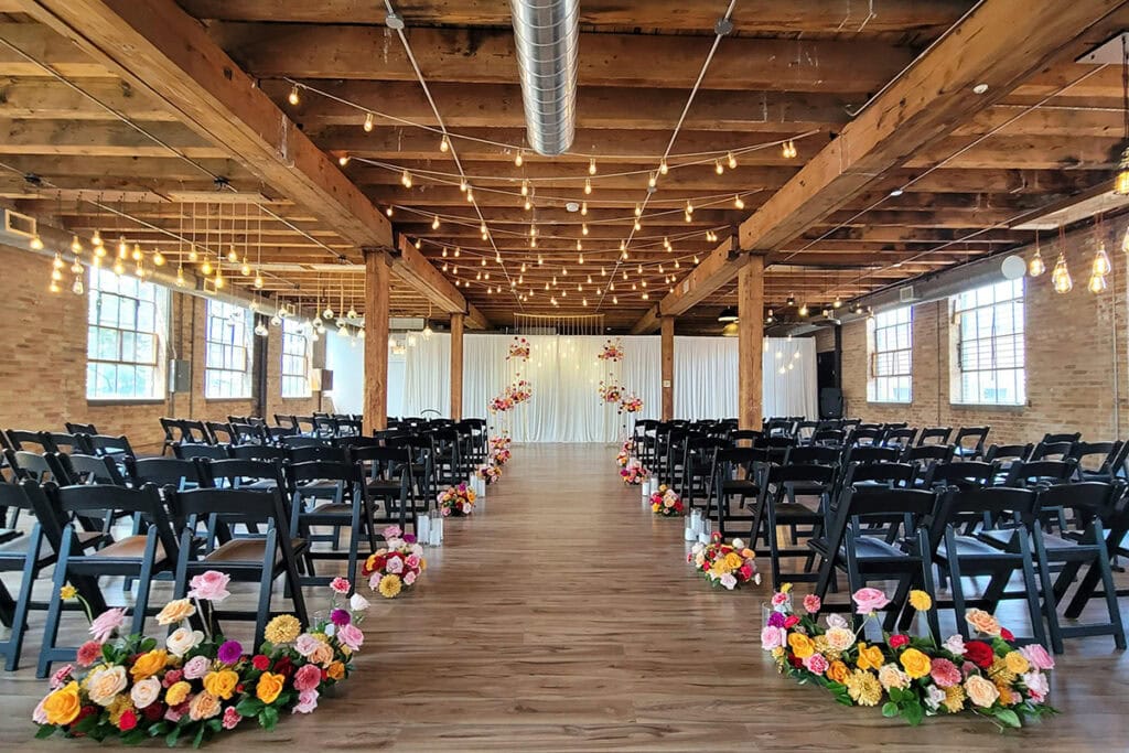 Tampa wedding planned indoors with wood ceilings, string lights, black chairs, and florals