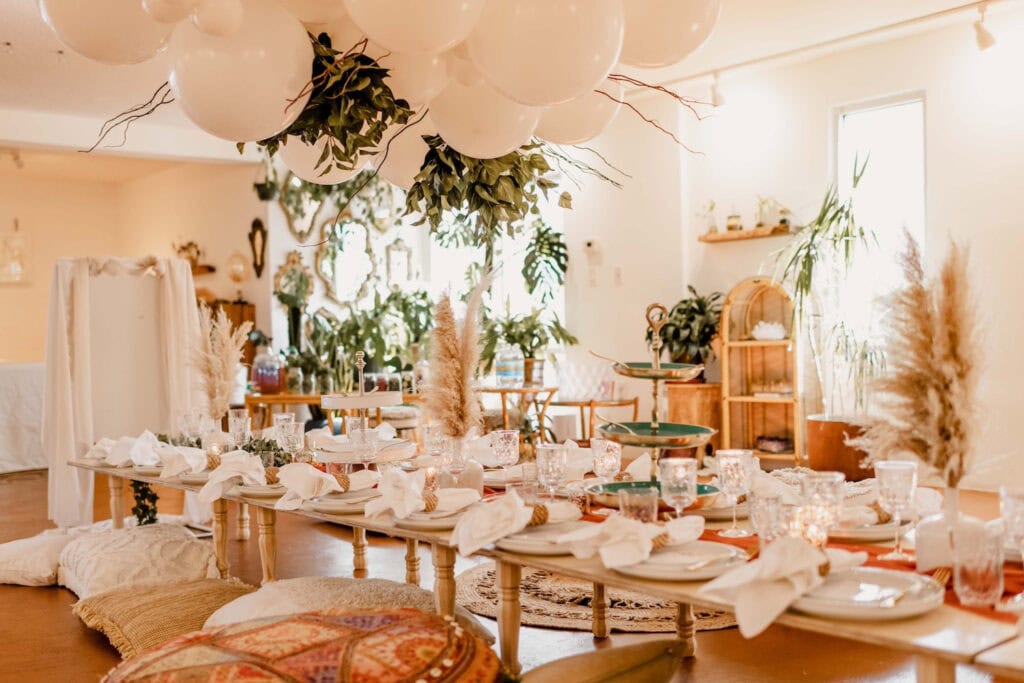 Low-lying tables are set with white and green accents in a bohemian style venue