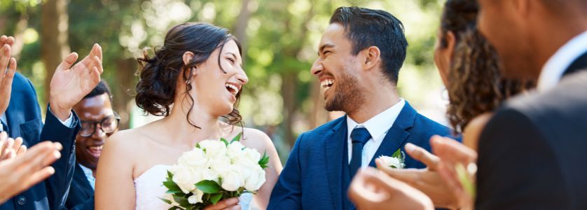 Bride and groom smiling with guests cheering, symbolizing the joy of weddings and the career path of how to become a wedding planner.