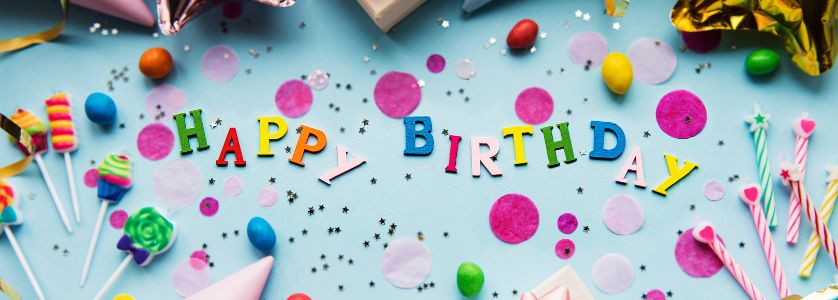 Colorful birthday decorations with confetti, candles, and candy spelling out “Happy Birthday” on a blue background — perfect for a guide on how to plan a birthday party.