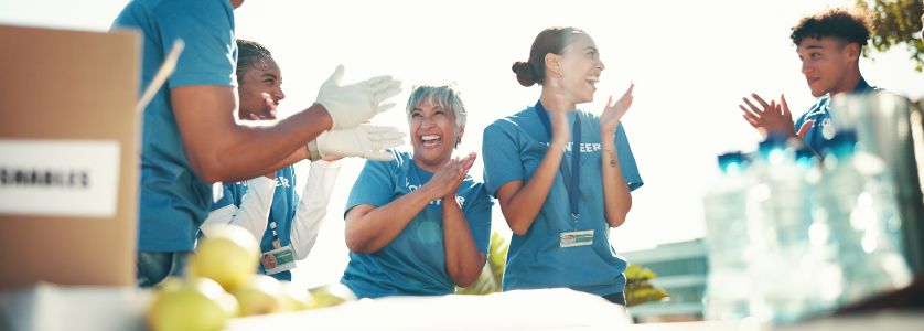 Volunteers celebrating at a successful charity event outdoors — an example of teamwork and community spirit when learning how to plan a fundraiser.