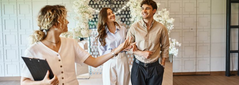 Event planner showing a couple a decorated venue, representing how to start an event planning business and attract clients.