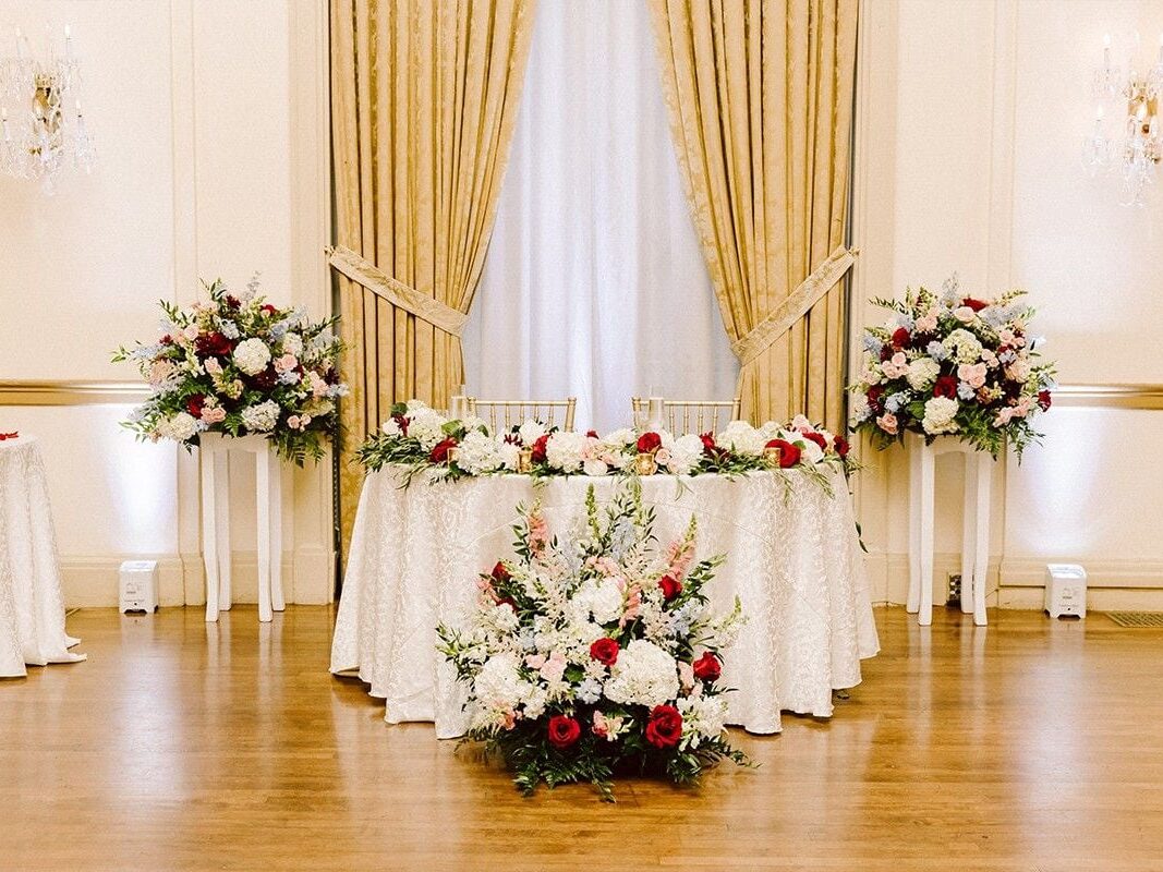 Sweetheart table with white cloth, florals, and curtain at Atlanta wedding
