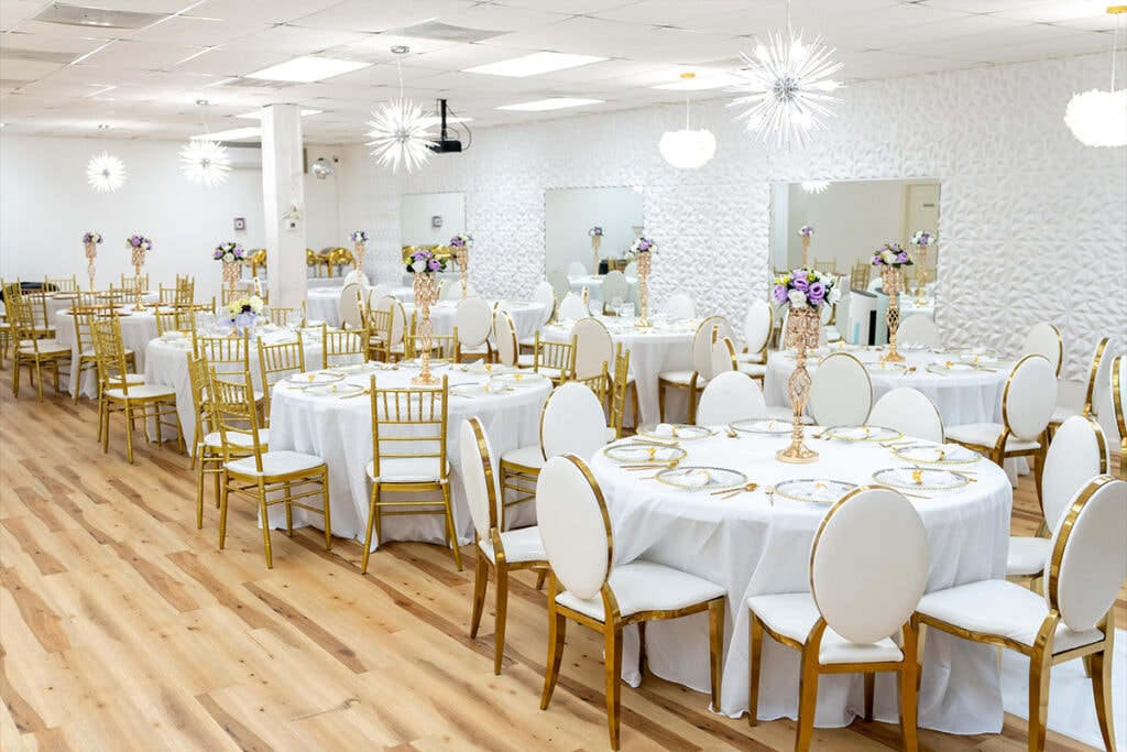 Indoor Nashville wedding venue with round tables, white tablecloths, gold accented chairs