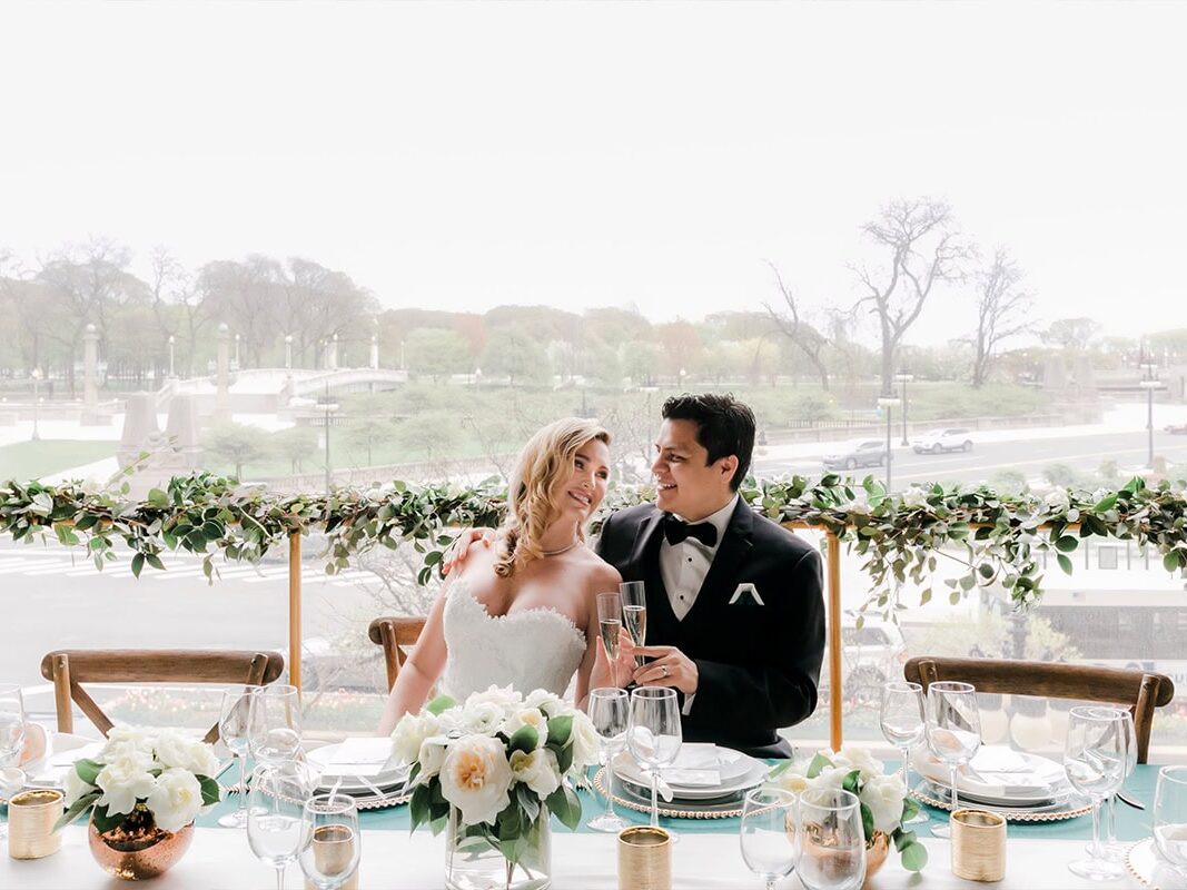 Couple seated at table outdoors with florals, garland, candles in Houston