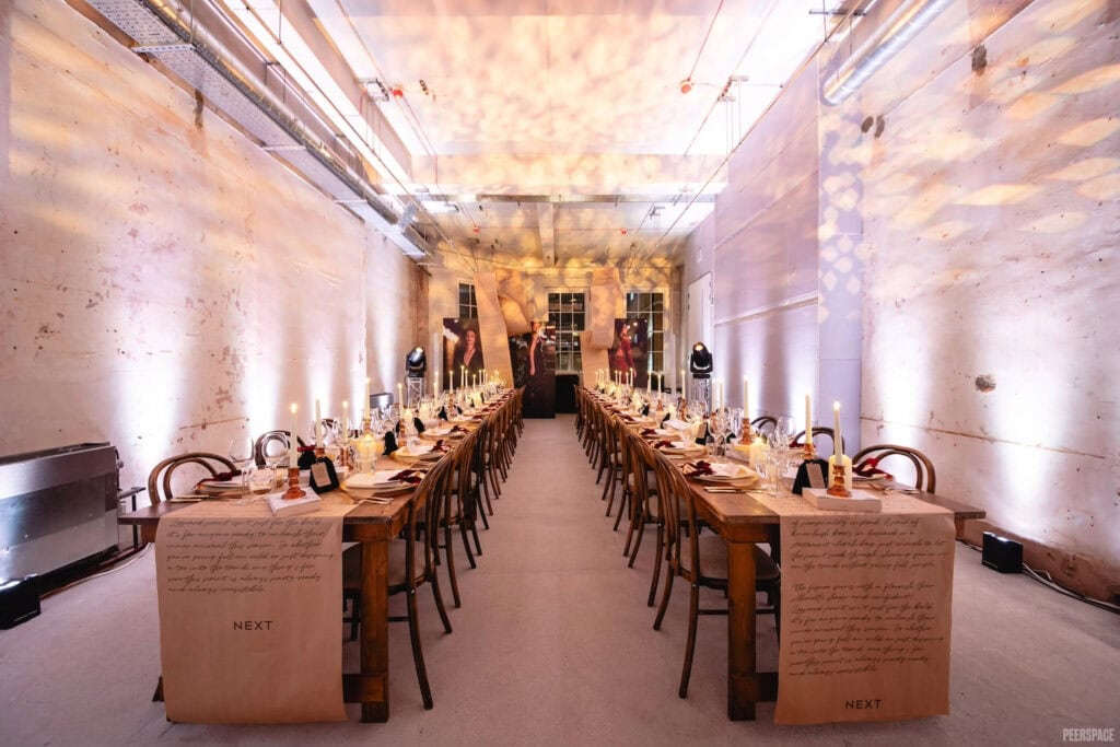 Dining tables are set with parchment paper runners in long, narrow room at English estate
