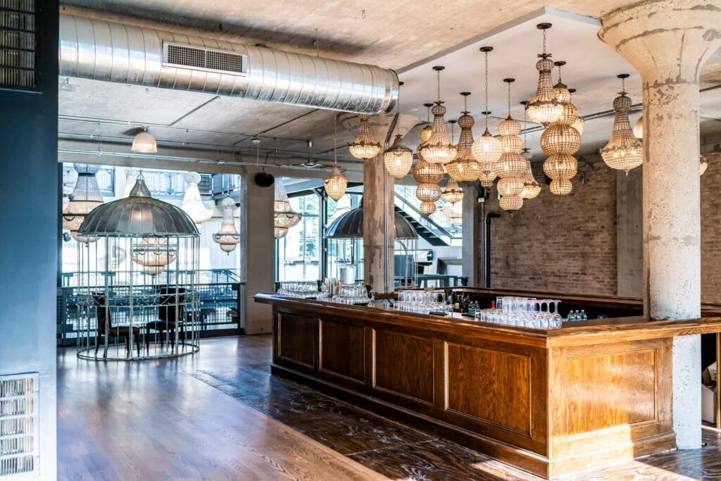Elegant bar illuminated by different sized chandeliers in a brightly-lit industrial space