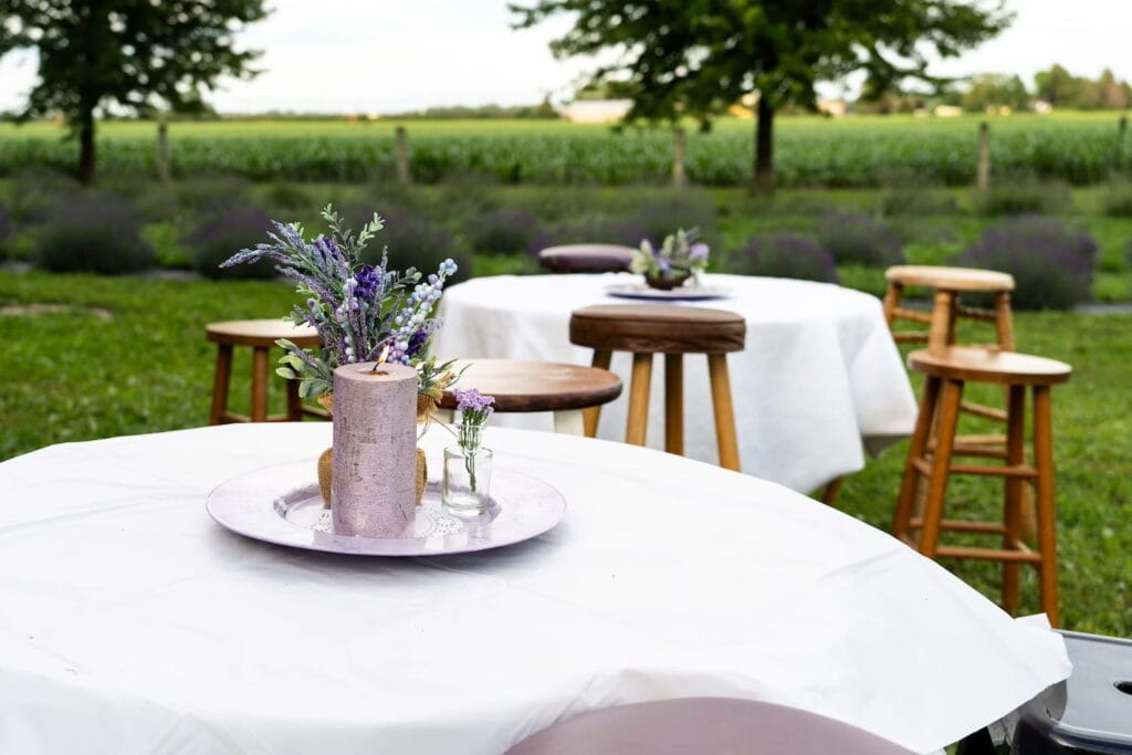 Round tables with stools sit outside in a field of lavender