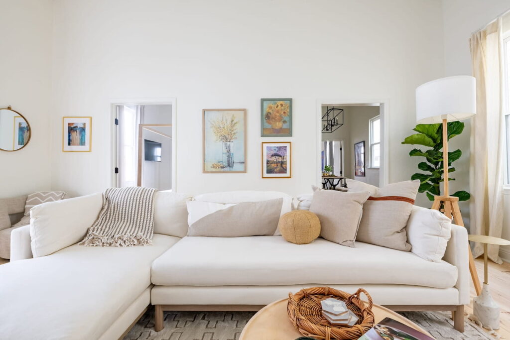 A dreamy New Orleans interior with a plush white couch and light wood decor in an all white room