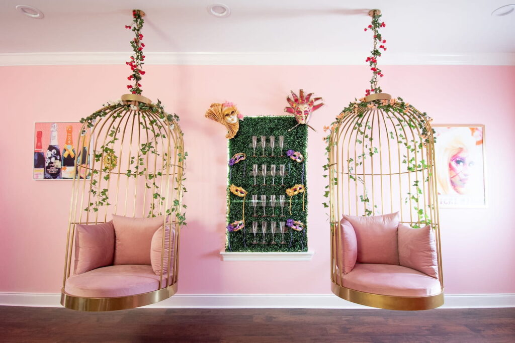 A pink room with two gold birdcage chairs hanging from the ceiling