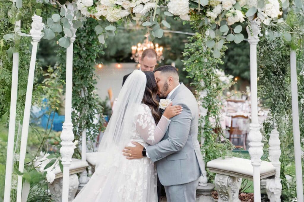 Bride and groom embracing under floral arch at San Francisco garden wedding