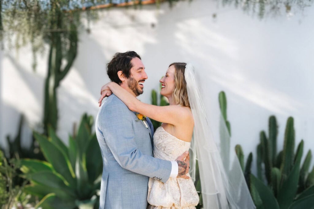 Couple embracing in front of succulents and white walls at Portland outdoor wedding