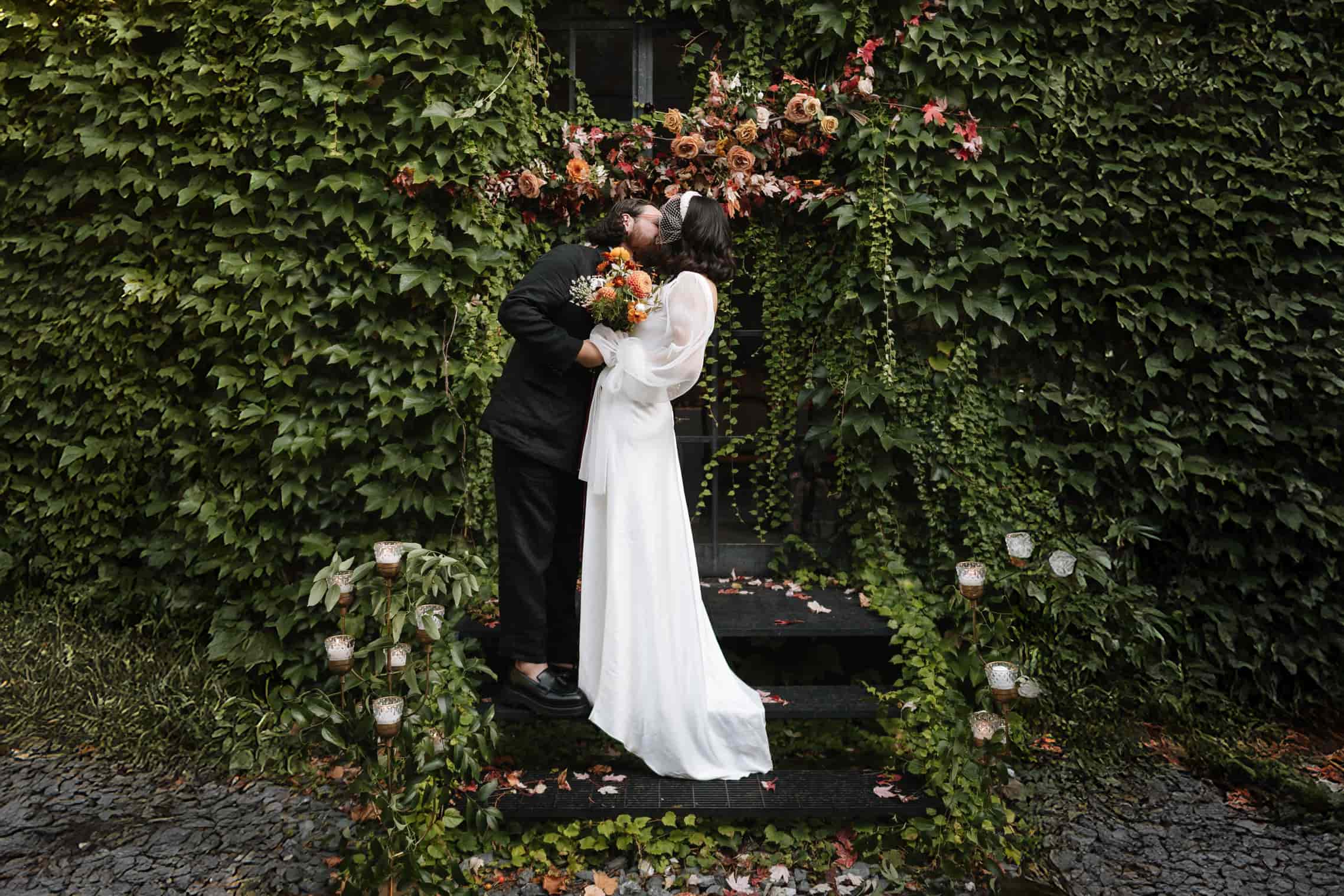Couple embracing near floral entrance at a lush Portland garden wedding