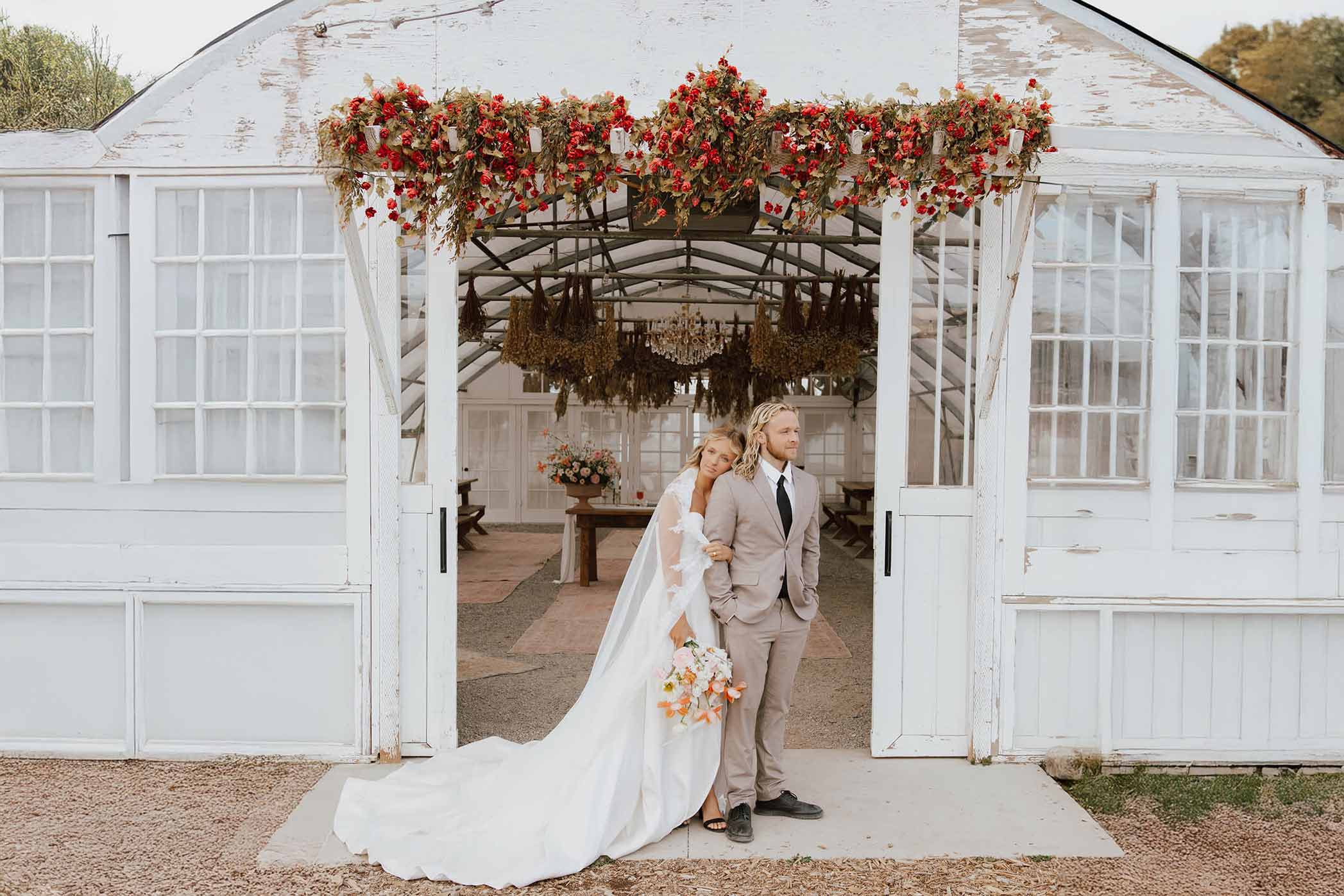 Wedding couple under floral arch at a rustic Portland greenhouse venue