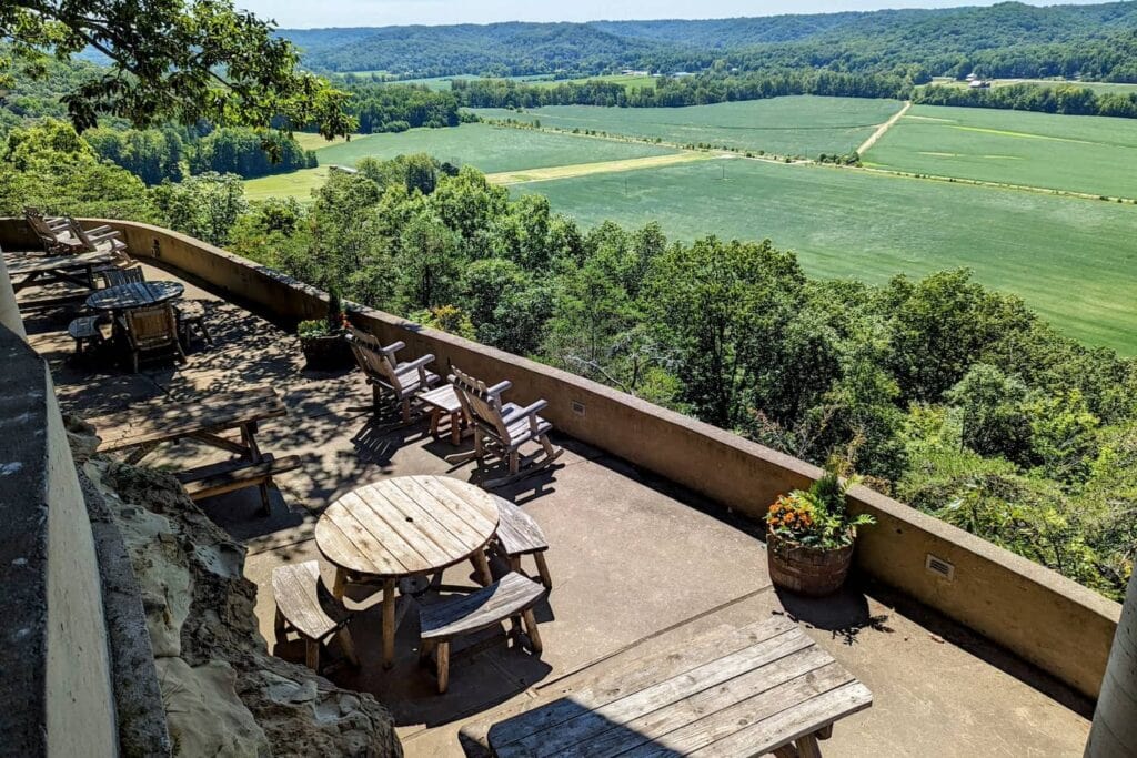 Large elevated patio space with separate seating areas overlooking large expanse of trees and fields in the distance