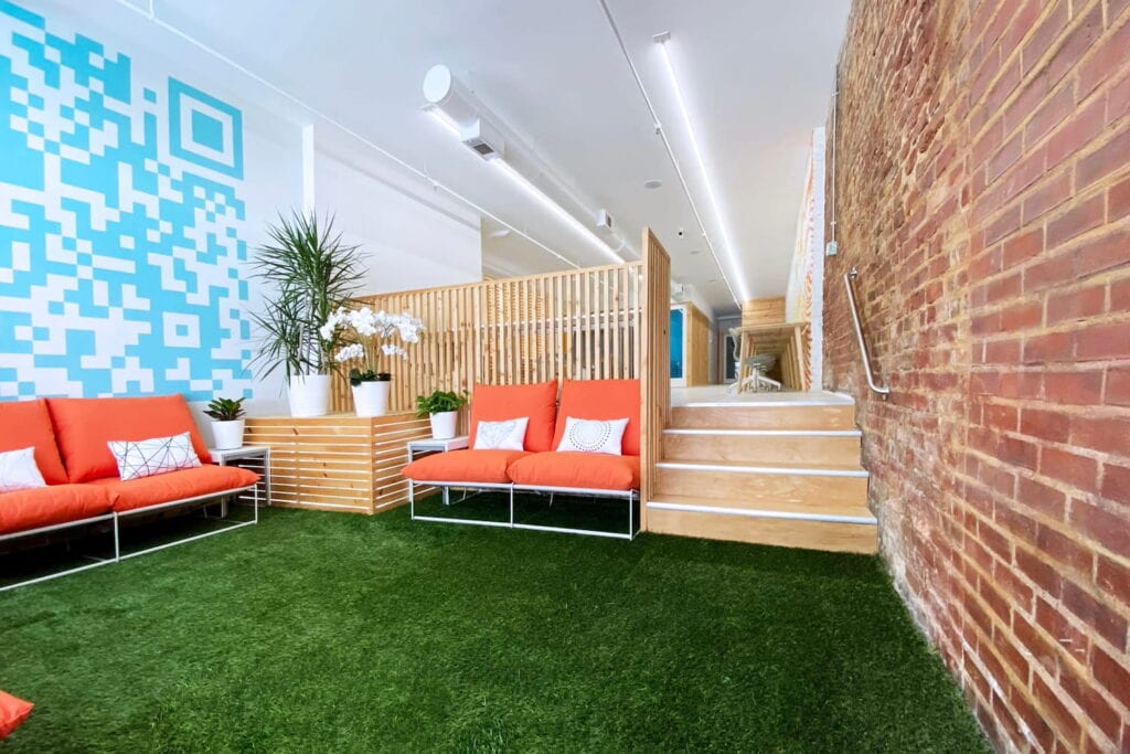 Brightly colored gathering space with orange couches and blue accents at an office in Atlanta