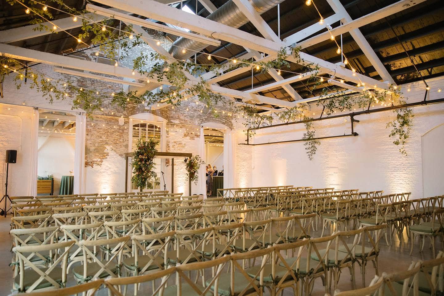 Rustic indoor Maine wedding ceremony space with string lights and brick walls