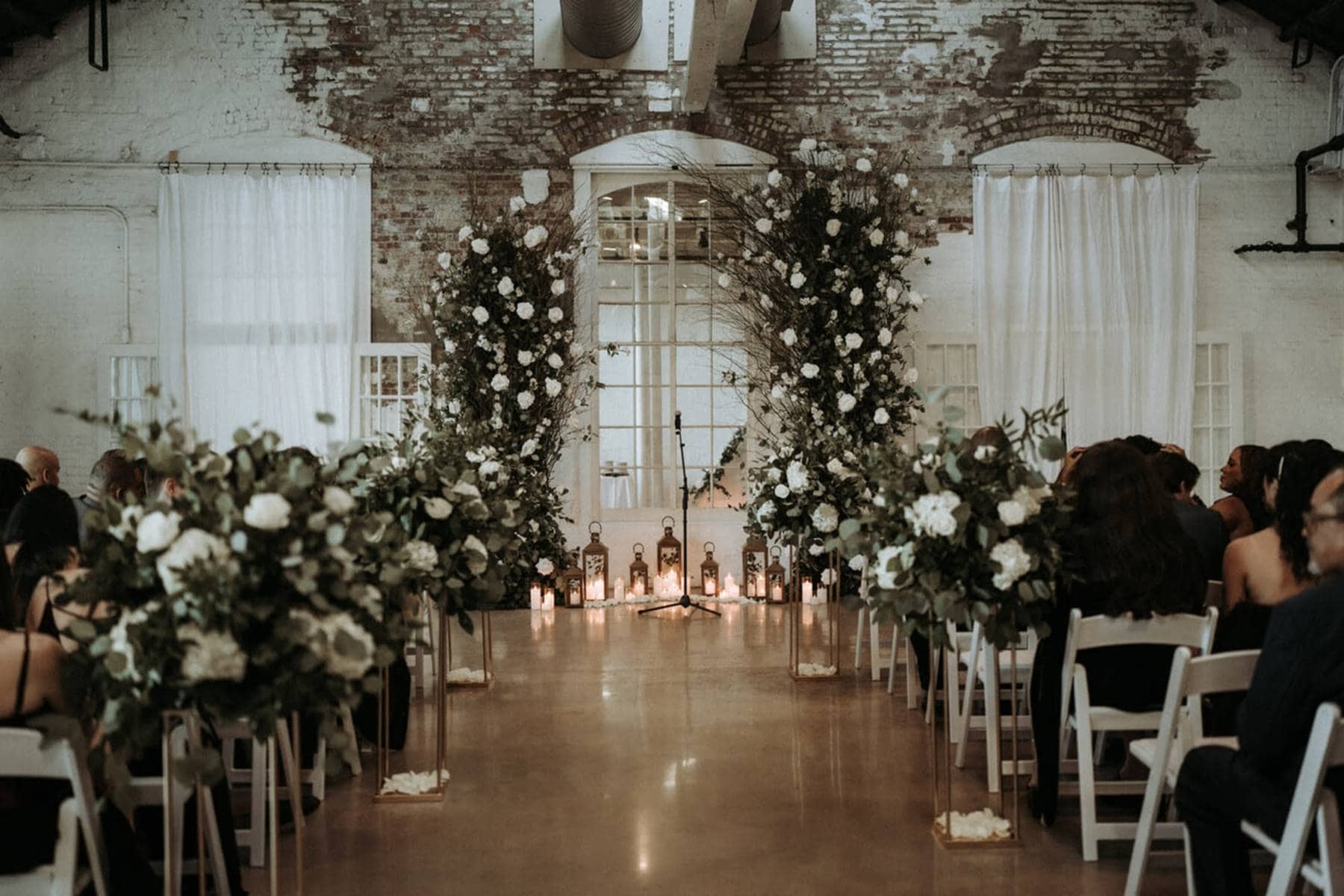 Indoor Cincinnati wedding ceremony setup with floral arch and brick walls