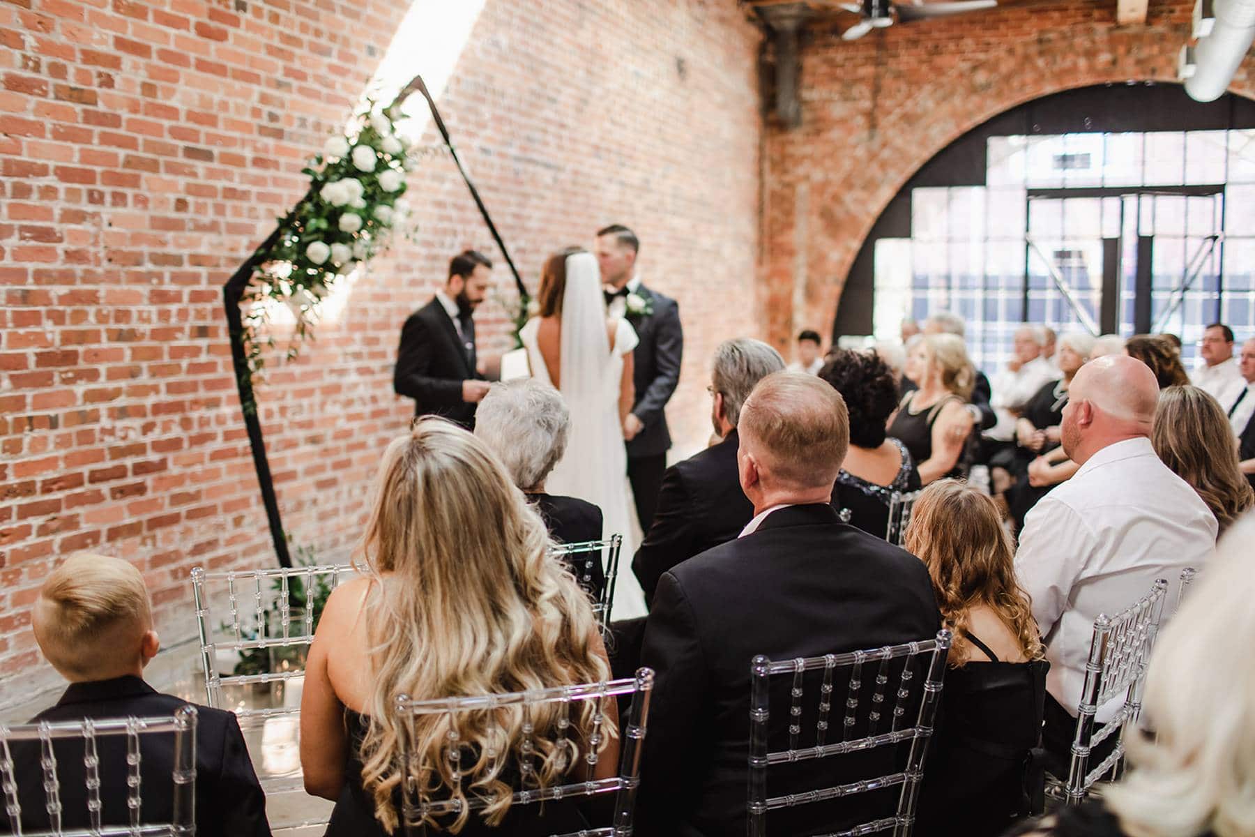 Couple exchanging vows under floral arch at Cincinnati industrial wedding venue