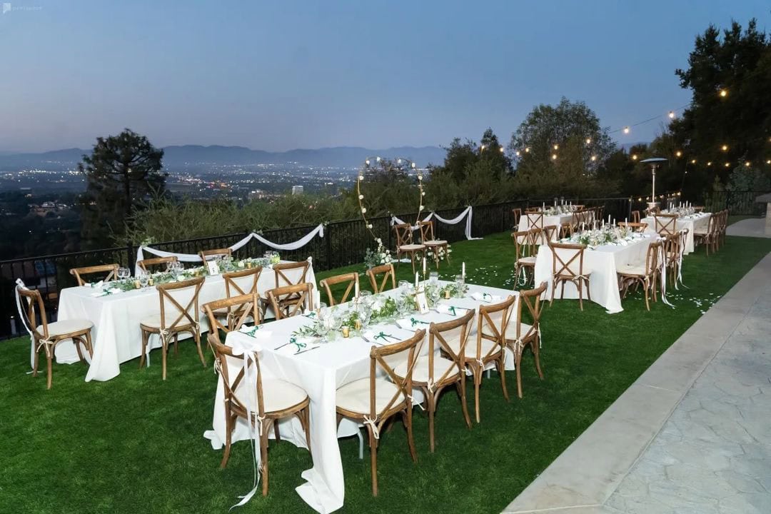 Outdoor reception setup on a lawn overlooking the Las Vegas city lights at twilight