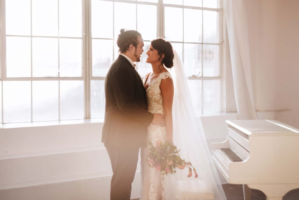 Bride and groom standing near a white piano at a Michigan wedding