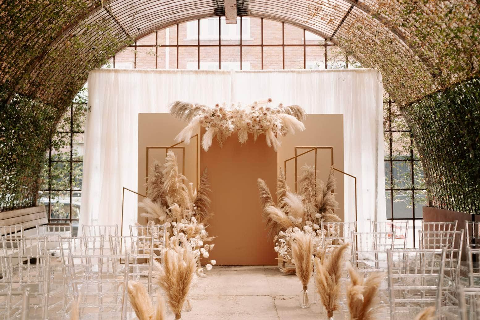 Greenhouse style Milwaukee wedding ceremony setup with pampas grass backdrop