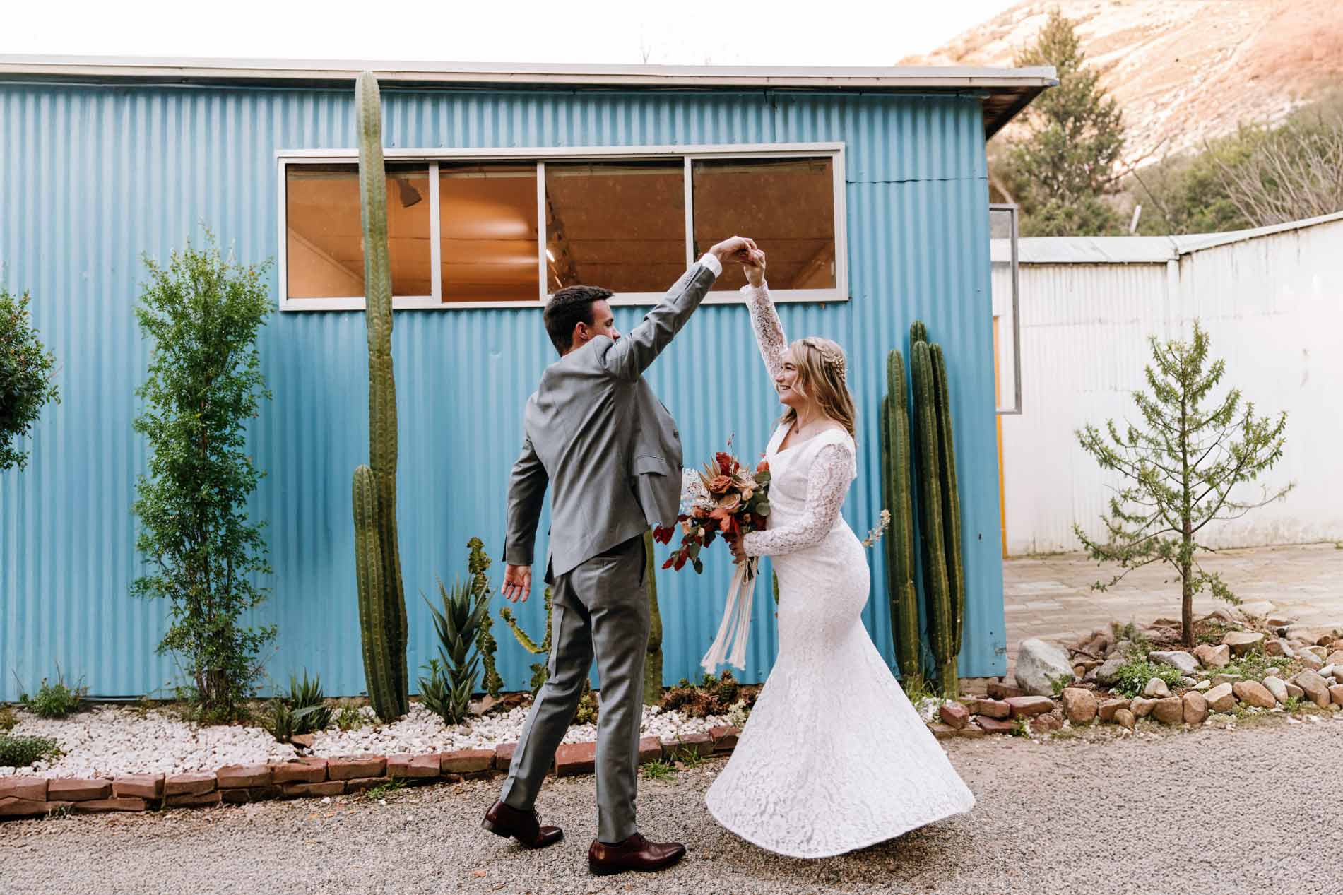 Couple celebrates outside a modern blue building with Las Vegas desert landscaping