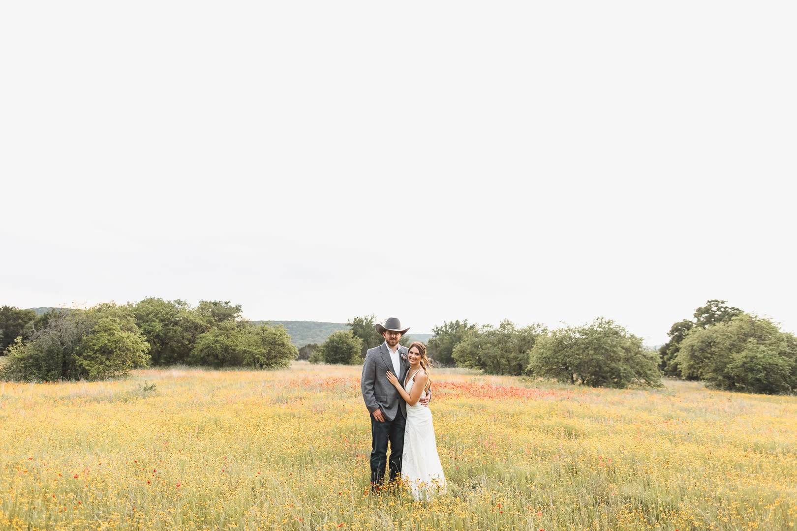 Bride and groom embracing in a scenic outdoor field near Tulsa