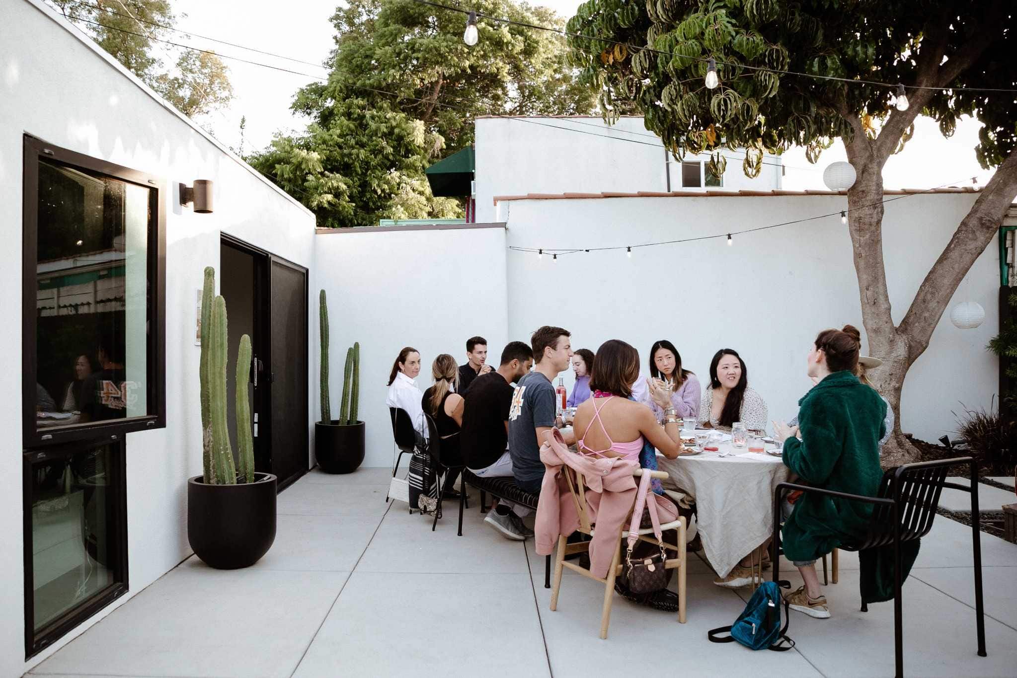 Group dining at a modern white courtyard party venue in Miami