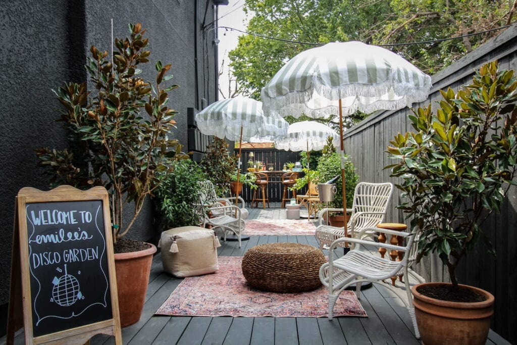A quaint outdoor garden venue with white umbrellas, a small bar areas and decorative plants
