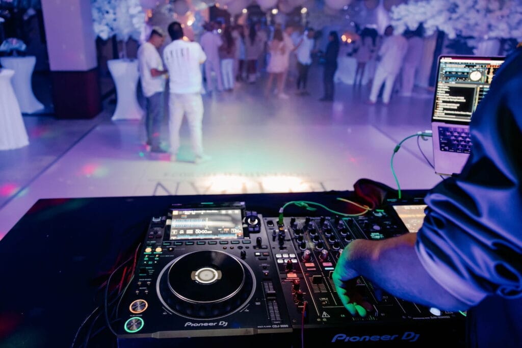 A DJs turntable in clear view at a party with patrons in the background