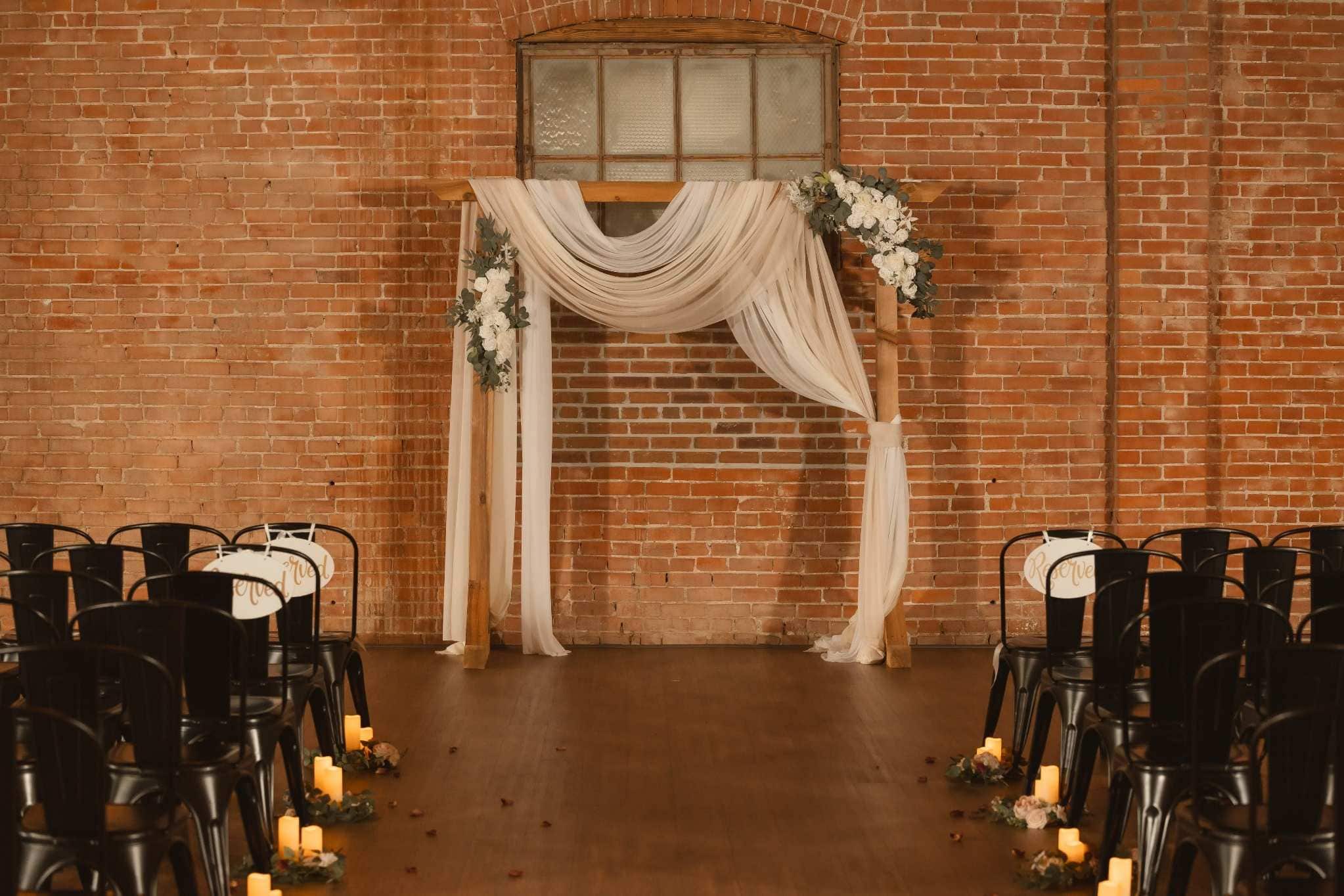 Indoor ceremony setup with floral arch in rustic Detroit venue