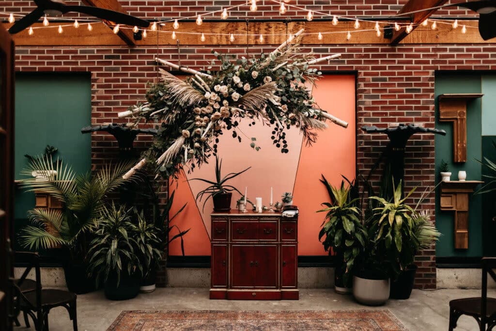 Greenery and florals accentuate a brick wall at a party space in St. Louis