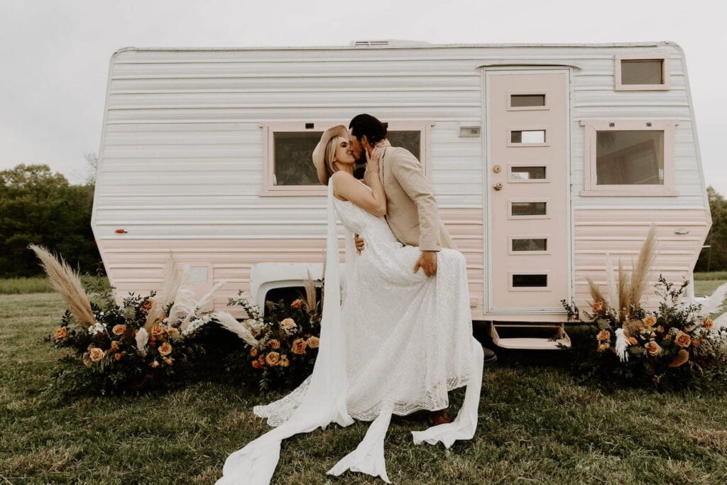 Bride and groom kissing outside a retro camper