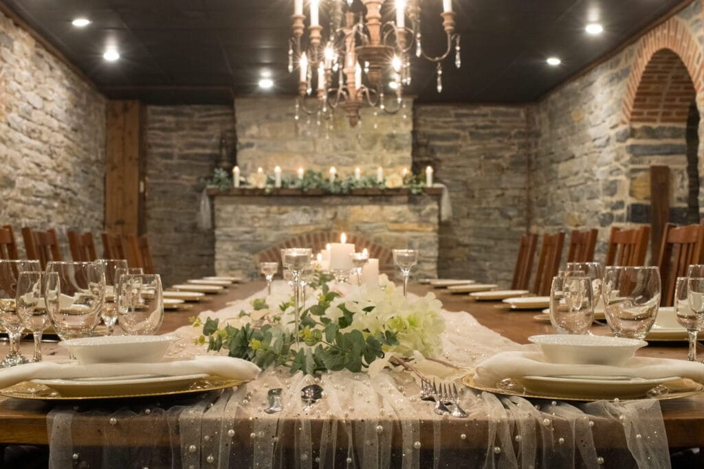 Intimate dining space at an Inn with a stone fireplace and wood beams, set up for a wedding reception